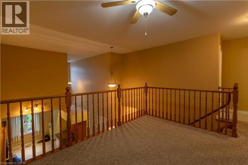Upper-level loft with neutral carpeting, wood-finish railing, and a ceiling fan with integrated lighting - 4066 Medland Drive, Burlington, ON - Indoor Photo Showing Other Room