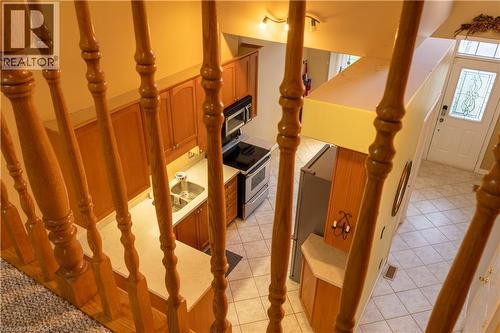 Open-concept kitchen and entryway featuring wood-finish cabinetry, stainless steel appliances, a double basin sink, and tiled flooring - 4066 Medland Drive, Burlington, ON - Indoor