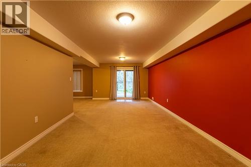 Expansive carpeted room featuring a bold accent wall, recessed lighting, and a sliding glass door - 4066 Medland Drive, Burlington, ON - Indoor Photo Showing Other Room