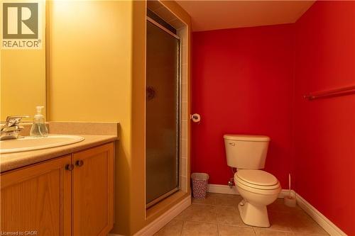 Bathroom featuring a wood-finish vanity with a built-in sink, a glass-enclosed shower, a toilet, and tile flooring - 4066 Medland Drive, Burlington, ON - Indoor Photo Showing Bathroom