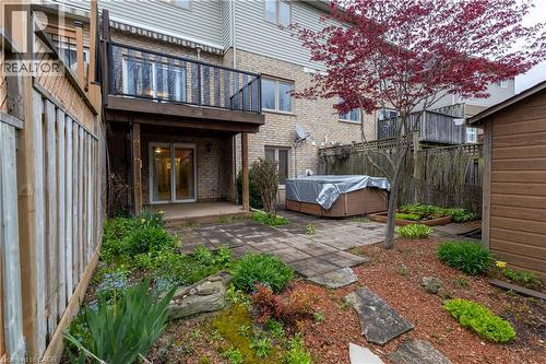 Patio and garden area featuring a wood deck with black metal railing, a ground-level patio with stone pavers, a hot tub, a detached storage shed, and a red-leafed tree - 4066 Medland Drive, Burlington, ON - Outdoor
