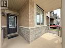 Covered front porch featuring a brick and stone facade, a dark paneled entry door with decorative glass, and a large window with stone trim - 3948 Thomas Alton Boulevard, Burlington, ON  - Outdoor With Exterior 