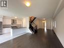 Open-concept living area featuring dark wood-finish flooring, a contemporary kitchen, and a staircase with dark wood newel posts and railings - 3948 Thomas Alton Boulevard, Burlington, ON  - Indoor Photo Showing Kitchen 