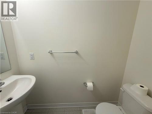 Pedestal sink with chrome faucet, wall-mounted mirror, and tile flooring - 3948 Thomas Alton Boulevard, Burlington, ON - Indoor Photo Showing Bathroom