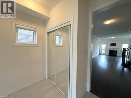 Entryway featuring tile flooring, mirrored closet doors, and recessed lighting, opening to a living area with dark wood-finish flooring and a fireplace - 3948 Thomas Alton Boulevard, Burlington, ON - Indoor Photo Showing Other Room