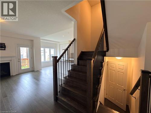 Staircase with dark wood treads and wrought iron balusters - 3948 Thomas Alton Boulevard, Burlington, ON - Indoor Photo Showing Other Room With Fireplace