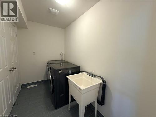 Dedicated utility room featuring dark gray tile flooring, a utility sink, and ample space for appliances - 3948 Thomas Alton Boulevard, Burlington, ON - Indoor Photo Showing Laundry Room