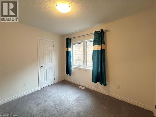 Carpeted room with a multi-pane window, flush-mount ceiling light, white baseboards, and a six-panel interior door - 3948 Thomas Alton Boulevard, Burlington, ON - Indoor Photo Showing Other Room