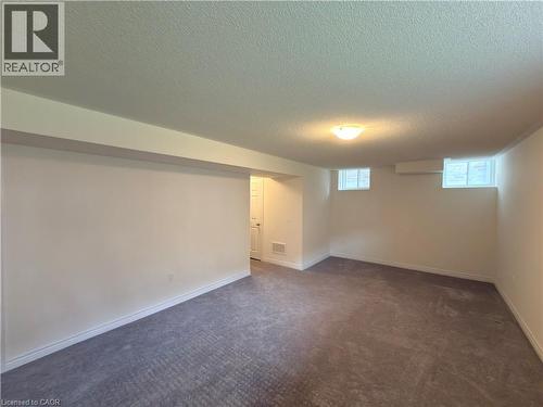 Spacious room featuring new carpeting, fresh neutral paint, white baseboards, and two window wells providing natural illumination - 3948 Thomas Alton Boulevard, Burlington, ON - Indoor