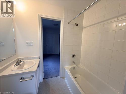 Bathroom featuring a vanity with an integrated sink and chrome faucet, a large wall-mounted mirror, and a tub-shower combination with white subway tile surround and chrome fixtures - 3948 Thomas Alton Boulevard, Burlington, ON - Indoor Photo Showing Bathroom