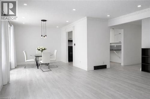 Open-concept living space featuring light wood-finish flooring, recessed lighting, and crown molding - 84 Elgar Avenue, Hamilton, ON 