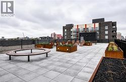 Expansive rooftop terrace featuring large format paver flooring, multiple decorative planters, and built-in seating elements - 