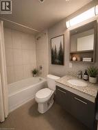 Bathroom featuring a white bathtub with subway tile surround, a toilet, a vanity with a light-colored speckled countertop, a built-in sink, and a modern medicine cabinet with open shelving - 