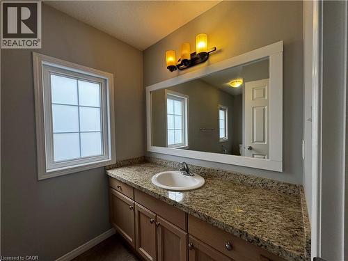 Vanity featuring an integrated sink, granite countertop, and light wood cabinetry with brushed nickel hardware - 13 Sorrento Street, Kitchener, ON - Indoor Photo Showing Bathroom