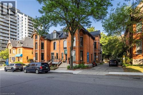 Brick facade building featuring multiple large arched windows, a prominent dormer roofline, and a multi-tiered entry staircase - 189 Hughson Street, Hamilton, ON 