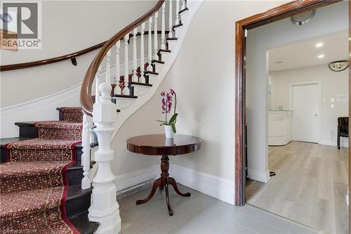 Grand staircase featuring a dark wood handrail, white balusters, and a decorative newel post - 189 Hughson Street, Hamilton, ON 