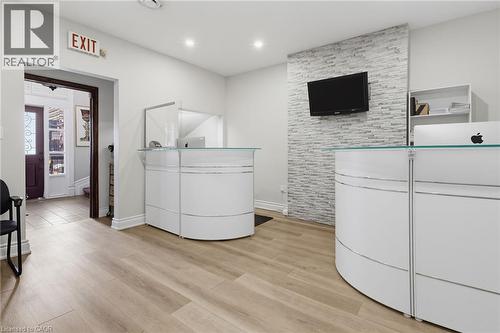 Reception area featuring light wood-finish flooring and two white reception desks with glass tops - 189 Hughson Street, Hamilton, ON 