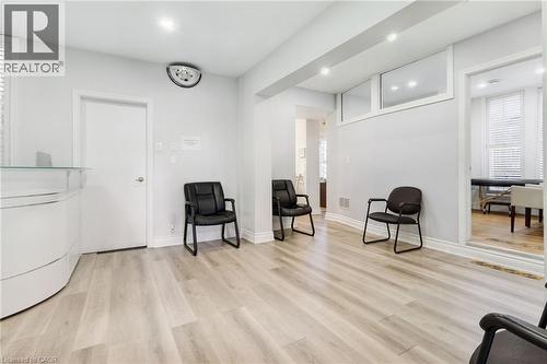 Reception area featuring light wood-finish flooring, recessed lighting, and a modern white reception desk with a glass top - 189 Hughson Street, Hamilton, ON 
