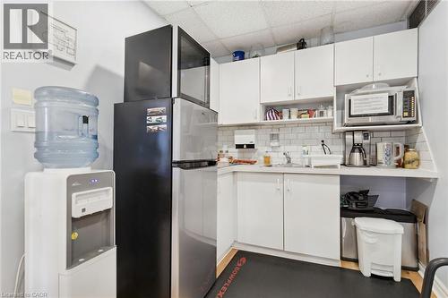 Compact kitchen area featuring white cabinetry, subway tile backsplash, and wood-finish flooring - 189 Hughson Street, Hamilton, ON 