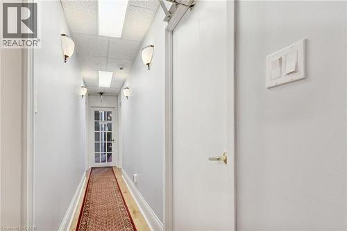 Hallway featuring wall sconces, recessed lighting, and a paneled glass door - 189 Hughson Street, Hamilton, ON 