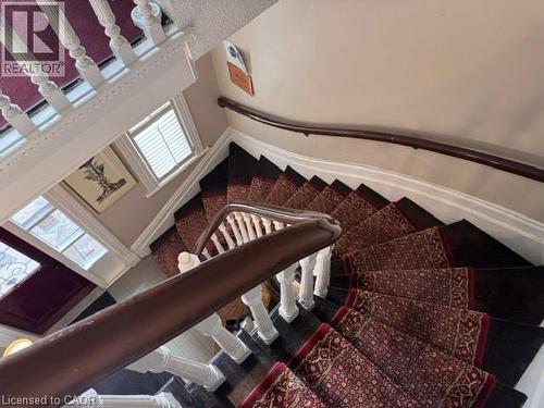 Curved dark wood staircase featuring a decorative runner, white balusters, and a rich wood handrail - 189 Hughson Street, Hamilton, ON 