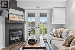 Dual French doors with grid-patterned glass, a contemporary fireplace with a dark-tiled surround, a floating mantel, and wood-finish flooring - 