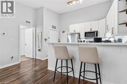 Kitchen featuring white cabinetry, stainless steel appliances, a breakfast bar, and wood-finish flooring - 