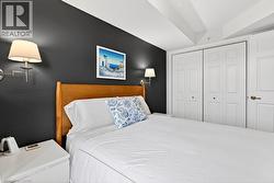 Bedroom featuring a dark accent wall, a light wood-finish headboard, and dual wall-mounted sconces - 