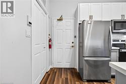 Entryway featuring wood-finish flooring, white paneled doors, and a stainless steel refrigerator - 