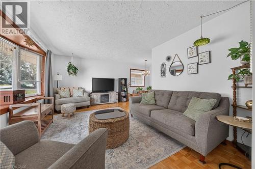 Living area featuring wood-finish flooring, a decorative chandelier, and an entertainment console with a built-in electric fireplace - 111 Kimberly Crescent, Kitchener, ON 