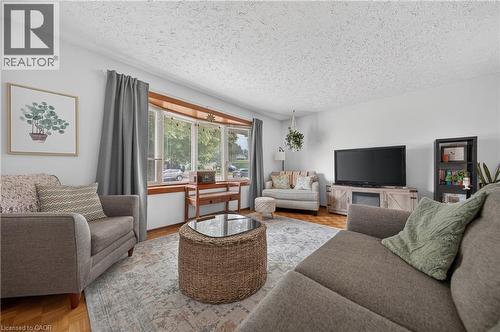 Bright living area featuring a bay window with wood trim, white walls, and wood-finish flooring - 111 Kimberly Crescent, Kitchener, ON 
