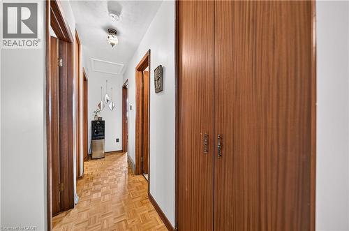 Hallway featuring parquet wood-finish flooring, white walls, and wood-finish doors with matching trim - 111 Kimberly Crescent, Kitchener, ON 