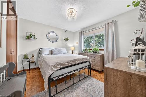 Spacious room featuring wood-finish flooring, a double window with light-filtering curtains, and a built-in closet with wood panel doors - 111 Kimberly Crescent, Kitchener, ON 