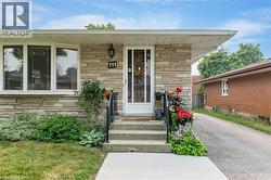 Front entrance featuring stone veneer siding, concrete steps with metal railings, a full-lite entry door, and a bay window - 