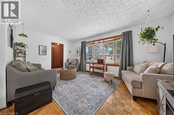 Bright living area featuring wood-finish parquet flooring and a large bay window - 