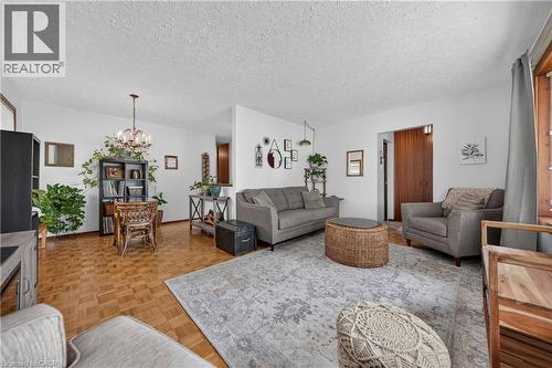 Open-concept room featuring wood-finish parquet flooring, white walls, and a chandelier with glass elements - 111 Kimberly Crescent, Kitchener, ON - Indoor Photo Showing Living Room