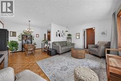 Open-concept room featuring wood-finish parquet flooring, white walls, and a chandelier with glass elements - 