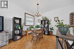 Dining area featuring wood-finish parquet flooring, a chandelier light fixture, and a window with a wood frame - 