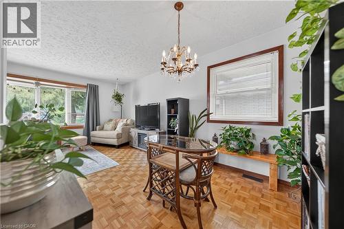 Parquet wood-finish flooring extends throughout this interior space, featuring a crystal chandelier and light grey walls - 111 Kimberly Crescent, Kitchener, ON - Indoor