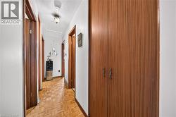 Hallway featuring parquet wood-finish flooring, white walls, and wood-finish doors with matching trim - 