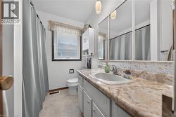 Bathroom featuring a vanity with an integrated sink, a laminate countertop, and ample storage cabinetry - 