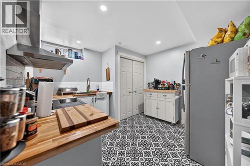 Kitchen featuring black and white patterned tile flooring, wood-finish countertops, subway tile backsplash, and a stainless steel range hood - 111 Kimberly Crescent, Kitchener, ON - Indoor