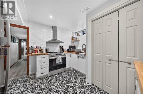 Kitchen featuring patterned floor tile, white subway tile backsplash, stainless steel range with overhead hood, and light wood-finish countertops - 111 Kimberly Crescent, Kitchener, ON - Indoor