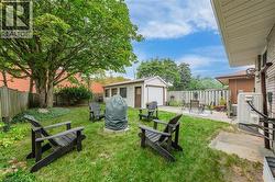 Expansive backyard featuring a mature tree, manicured lawn, and a detached garage with a white overhead door - 