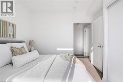 Bedroom featuring light wood-finish flooring, white walls, and a white panel door with black hardware - 