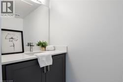 Powder room featuring a dark vanity with a white countertop, an integrated rectangular sink, a polished chrome faucet, and a large wall-mounted mirror - 