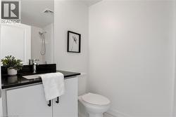 Bathroom featuring a white vanity with black hardware, a black countertop, a chrome faucet, and a wall-mounted mirror - 