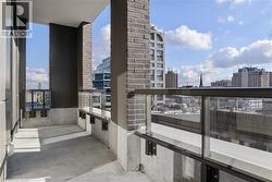 Exterior balcony featuring concrete flooring, a glass and metal railing system, and brick-clad wall sections - 