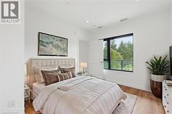 Spacious bedroom featuring light wood-finish flooring, a contemporary window, white walls, recessed lighting, and a neutral color palette - 