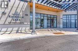 Modern building entrance featuring a prominent nameplate, extensive glass storefront, and a covered entry with a contemporary pergola structure - 